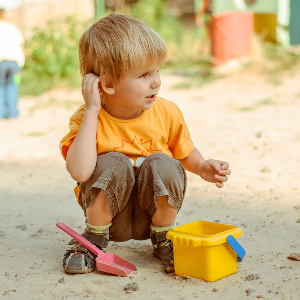 Маленький мальчик играет на песке 