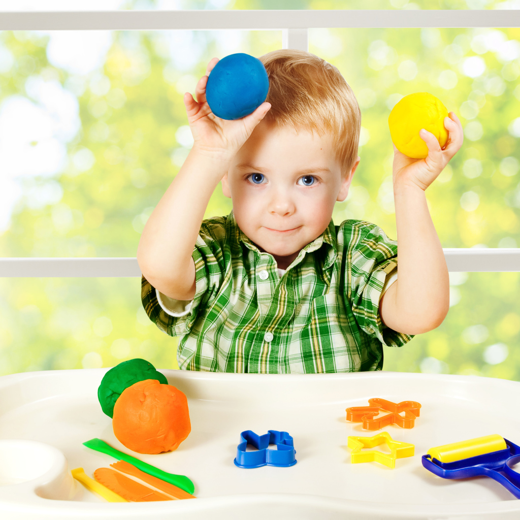 Маленький мальчик играет с игрушками у окна