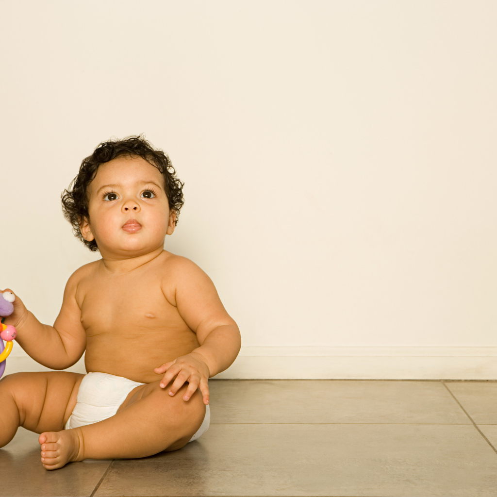 Маленький мальчик сидит на полу с игрушкой