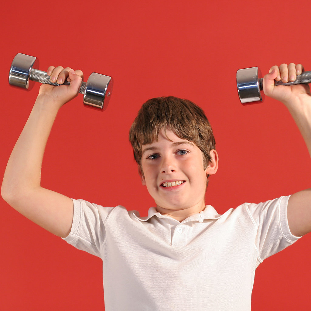Маленький мальчик с гантелями на красном фоне