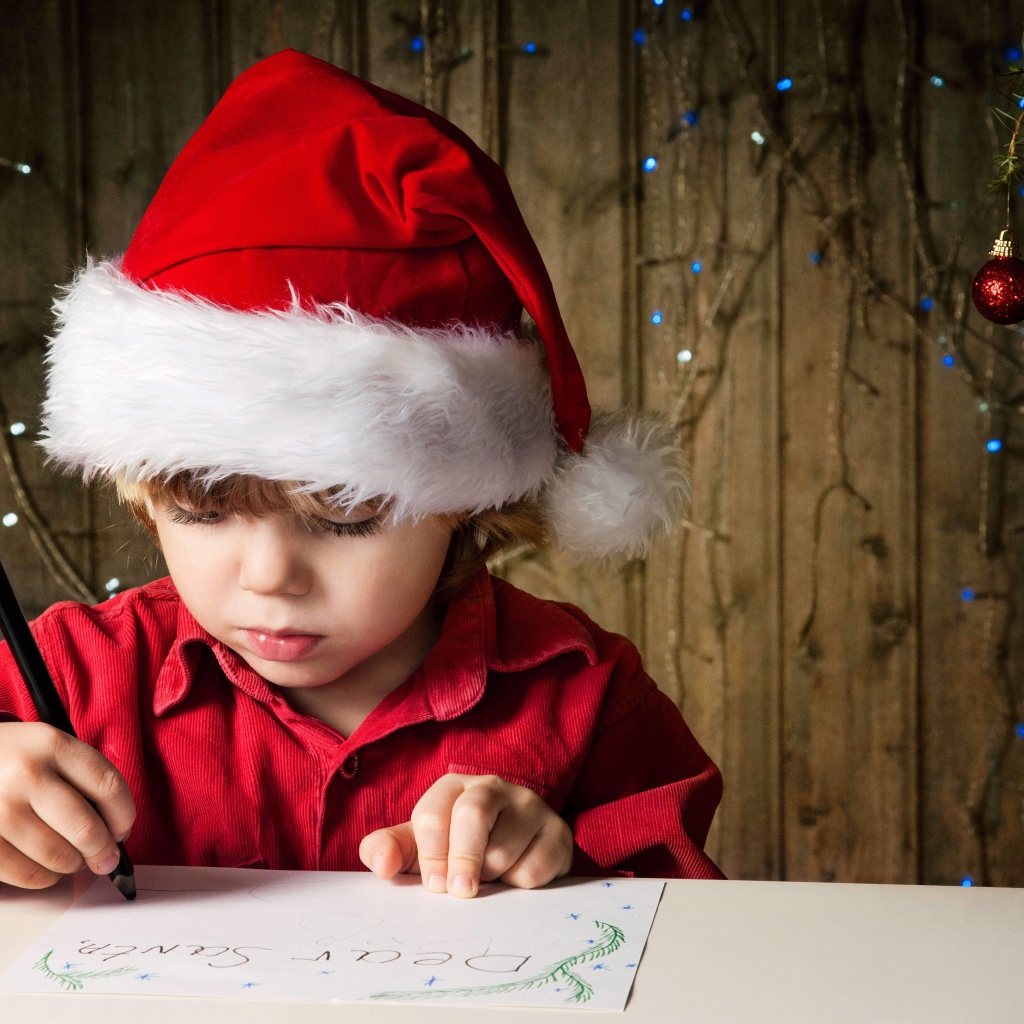 Маленький мальчик пишет письмо Деду Морозу 