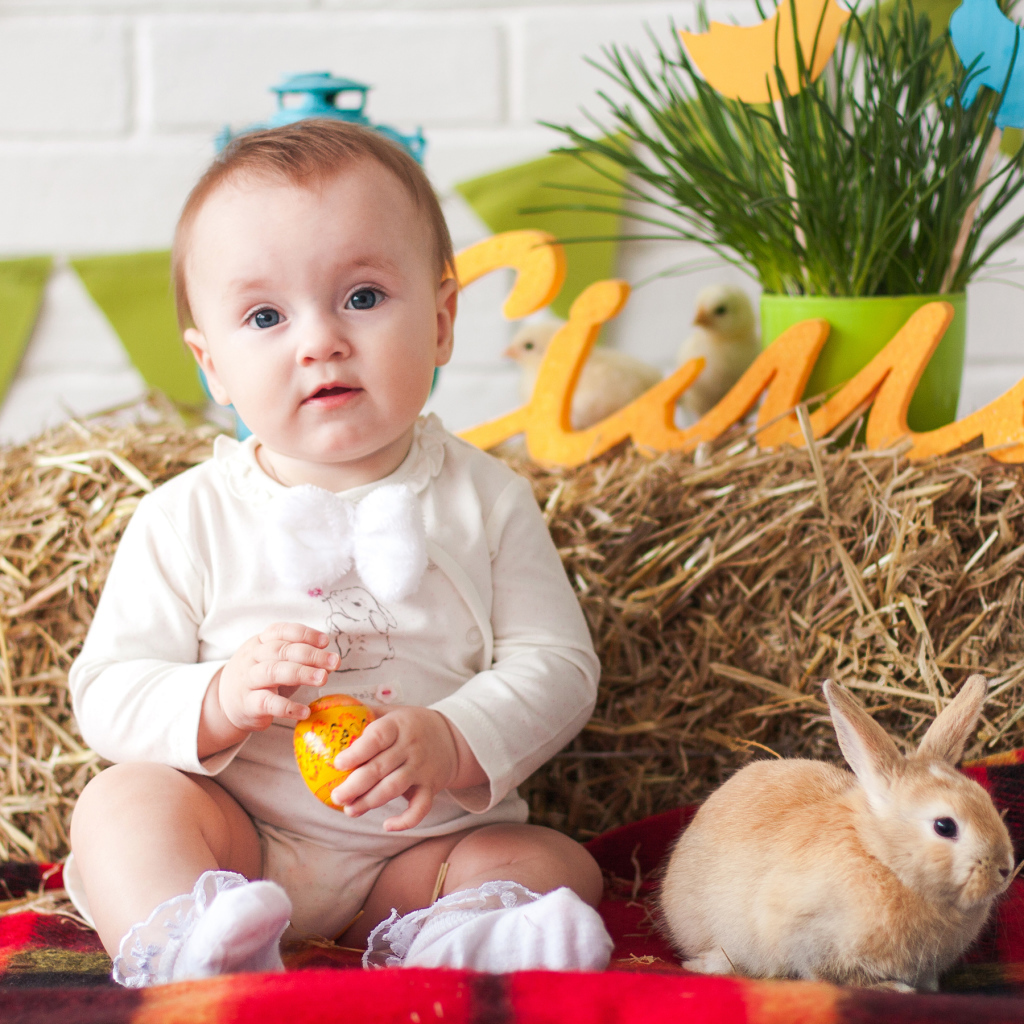 Маленький ребенок с крашеным яйцом и декоративным кроликом