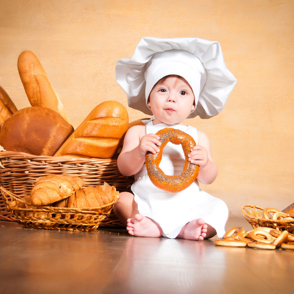 Маленький поваренок на столе со свежей выпечкой