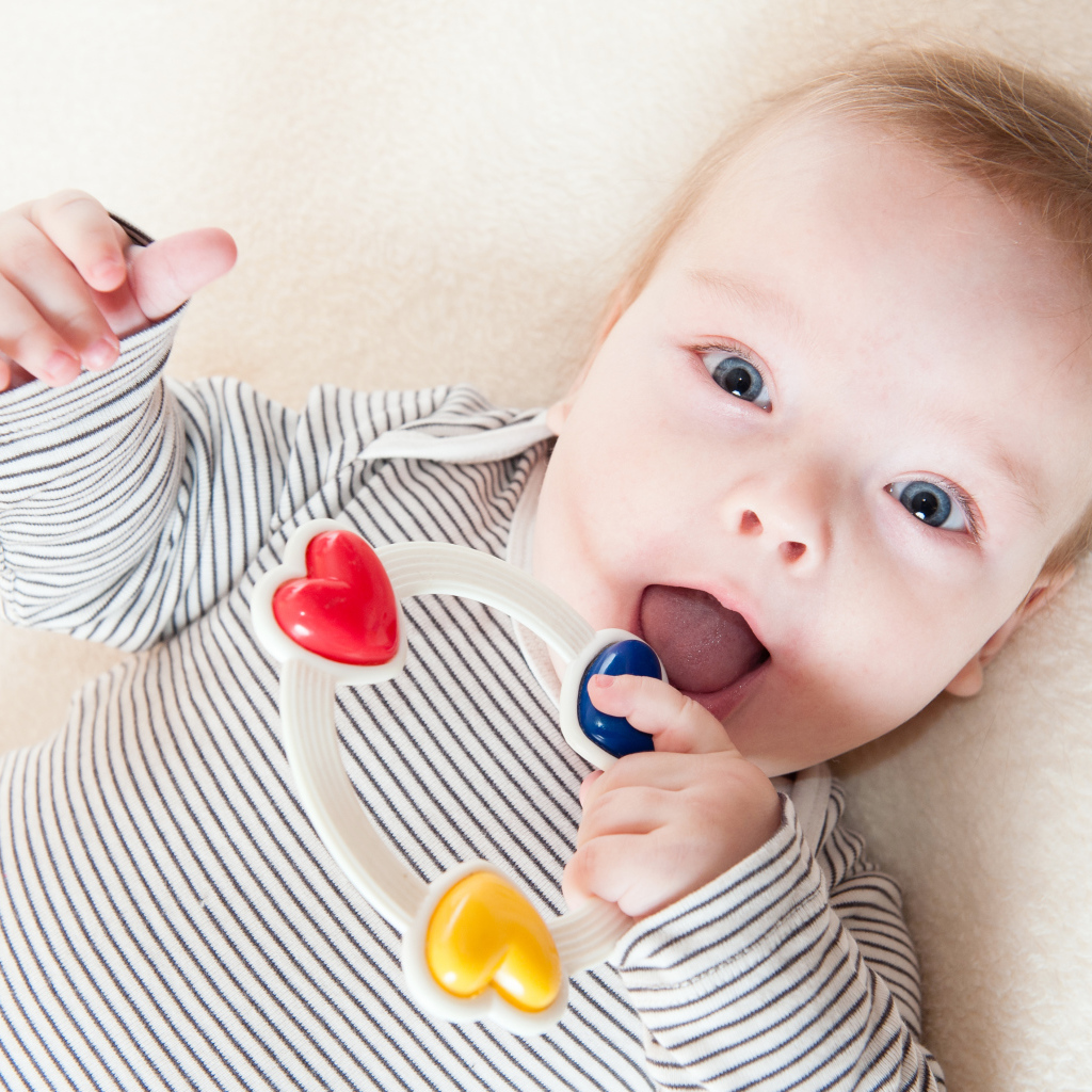 Маленький забавный голубоглазый ребенок с погремушкой