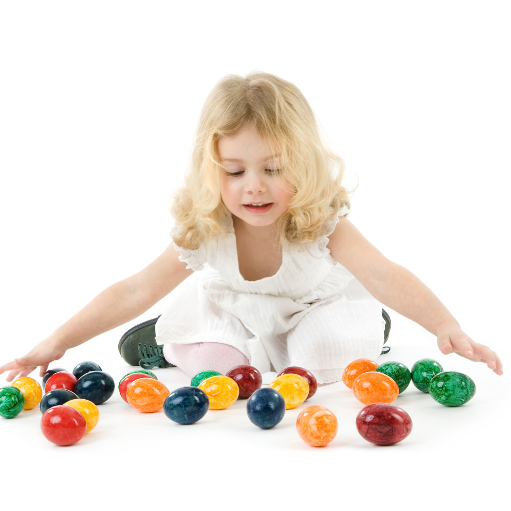 Маленькая девочка блондинка с крашеными яйцами на белом фоне