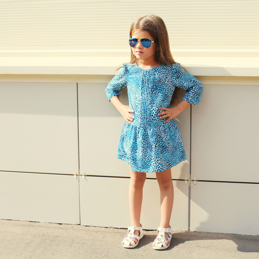 Маленькая девочка в красивом платье у стены