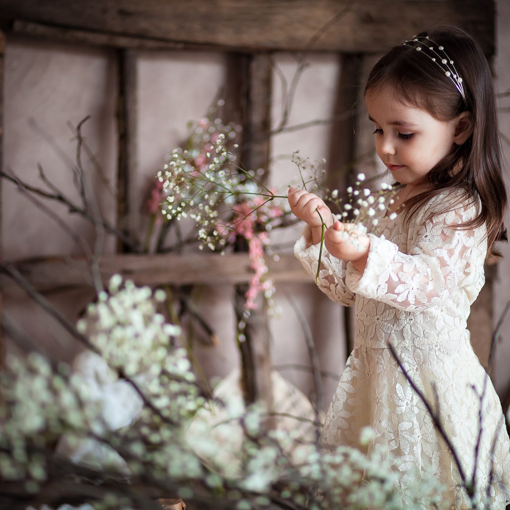Маленькая девочка в красивом платье с белыми цветами в руке