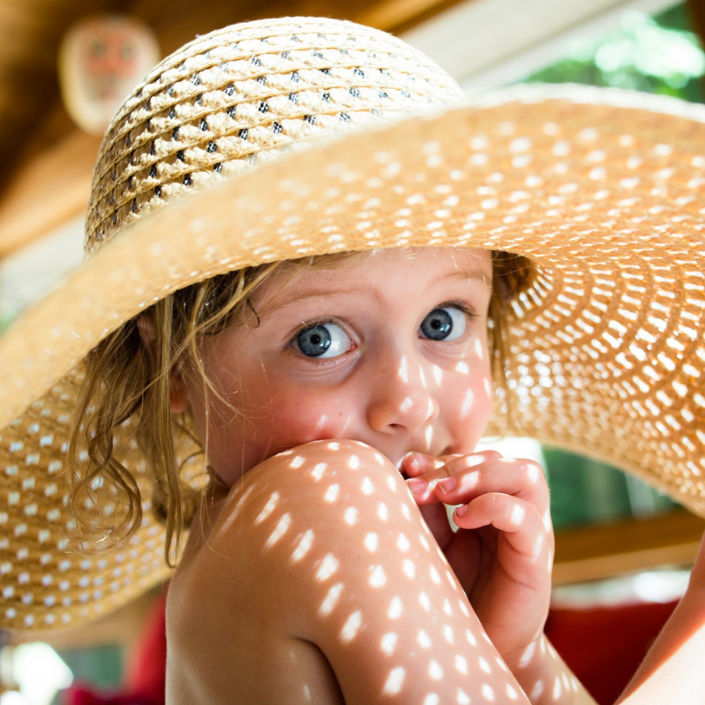Маленькая девочка в большой соломенной шляпе летом