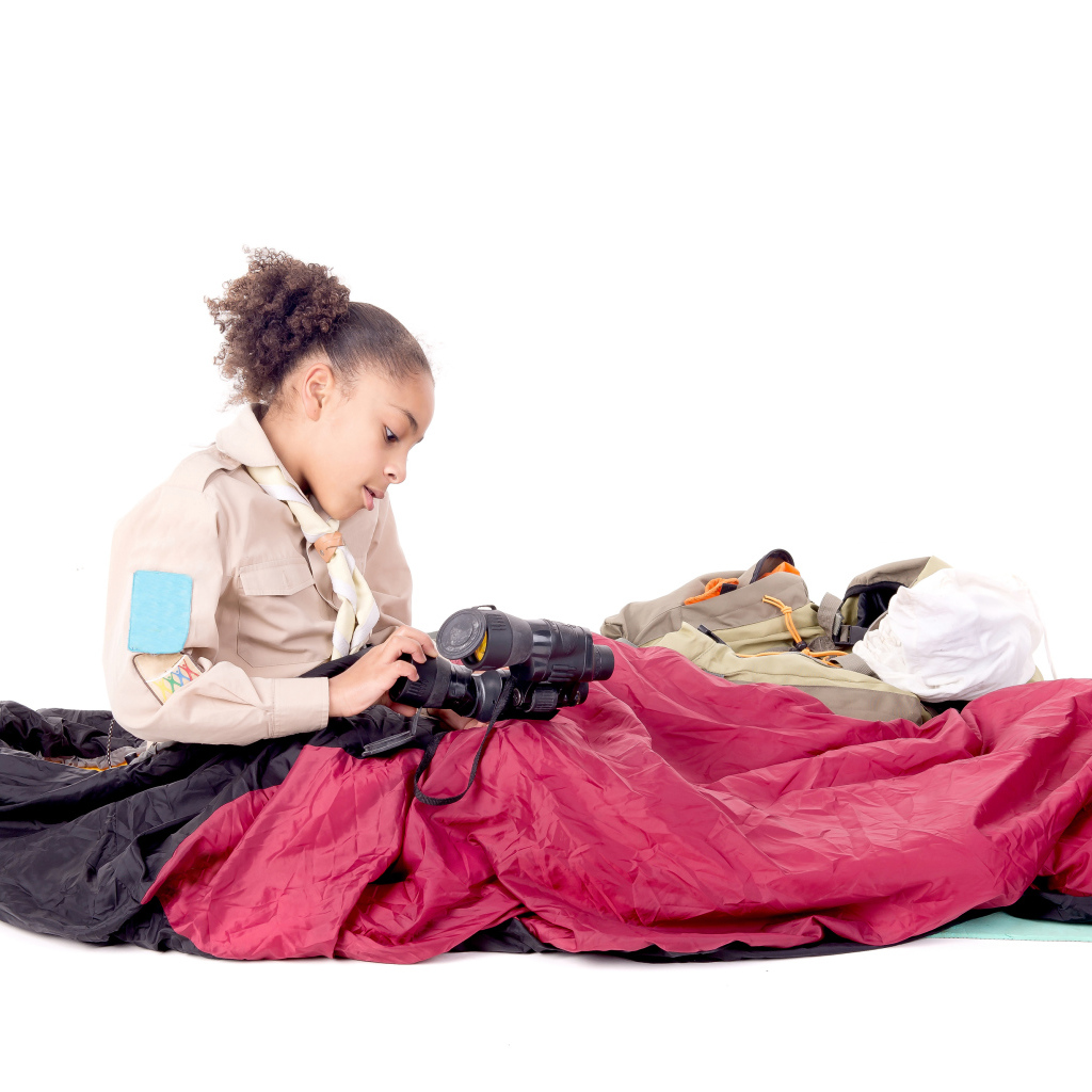 Маленькая девочка в спальном мешке с биноклем