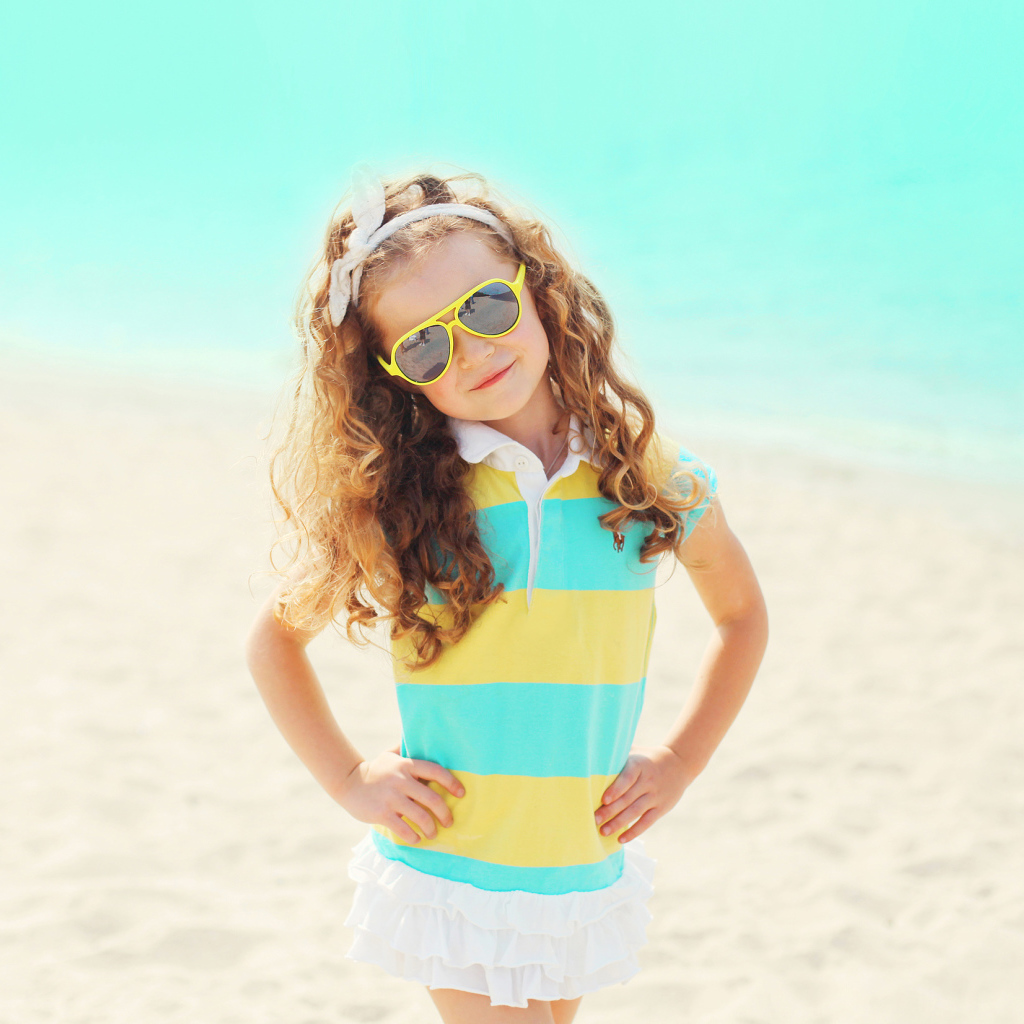 Маленькая девочка в солнечных очках на пляже
