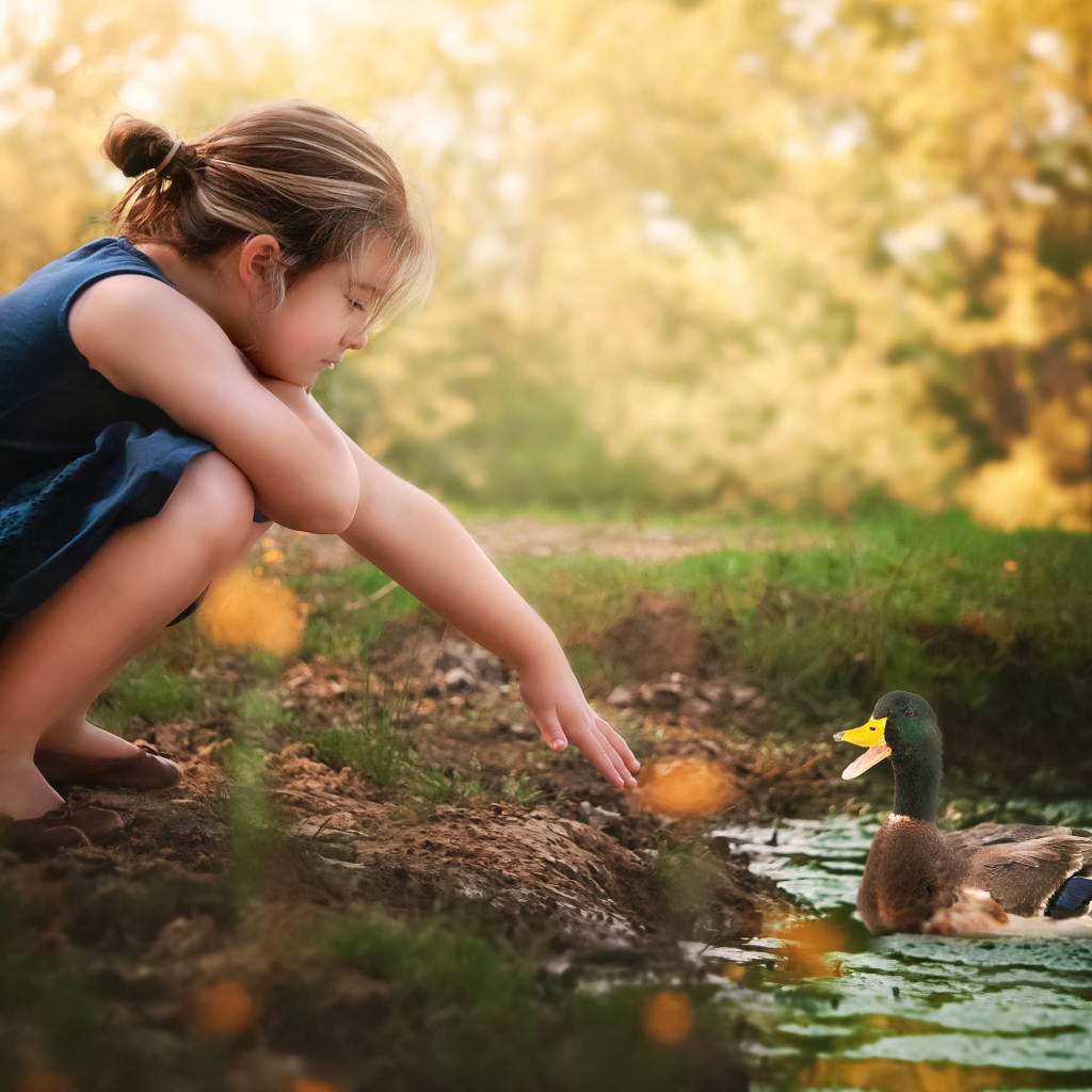 Маленькая девочка играет с уточкой в воде