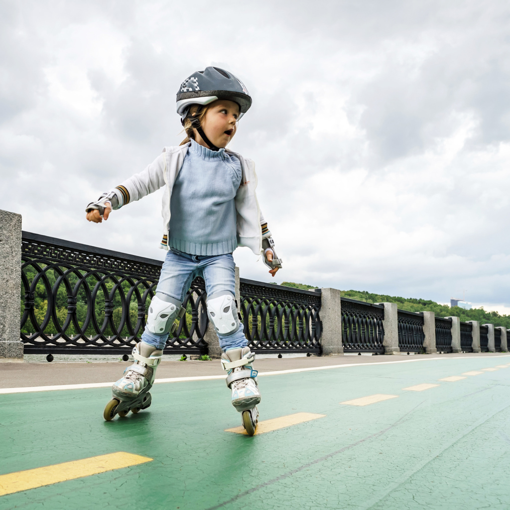 Маленькая девочка катается по мосту на роликах