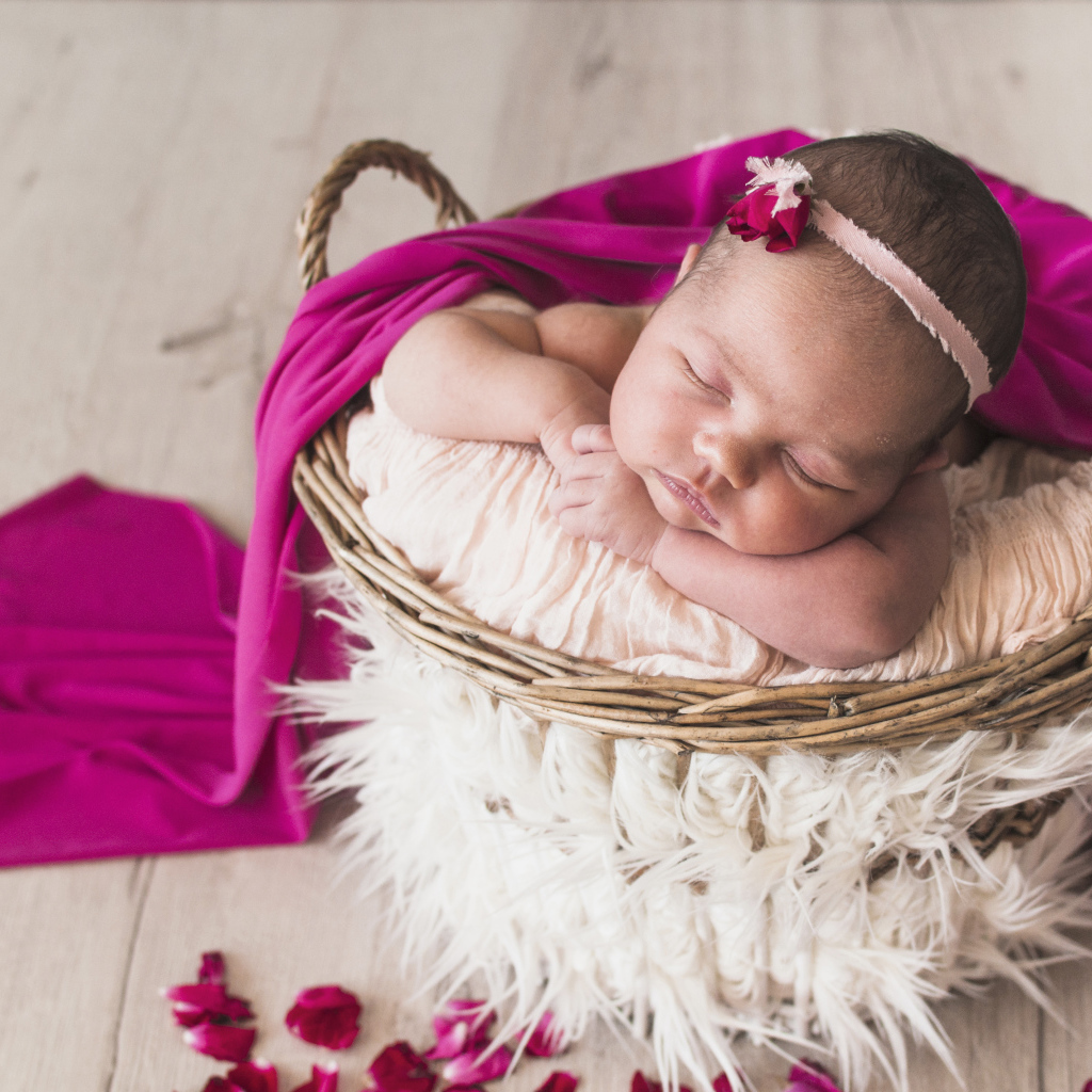Маленькая девочка спит в корзине под покрывалом