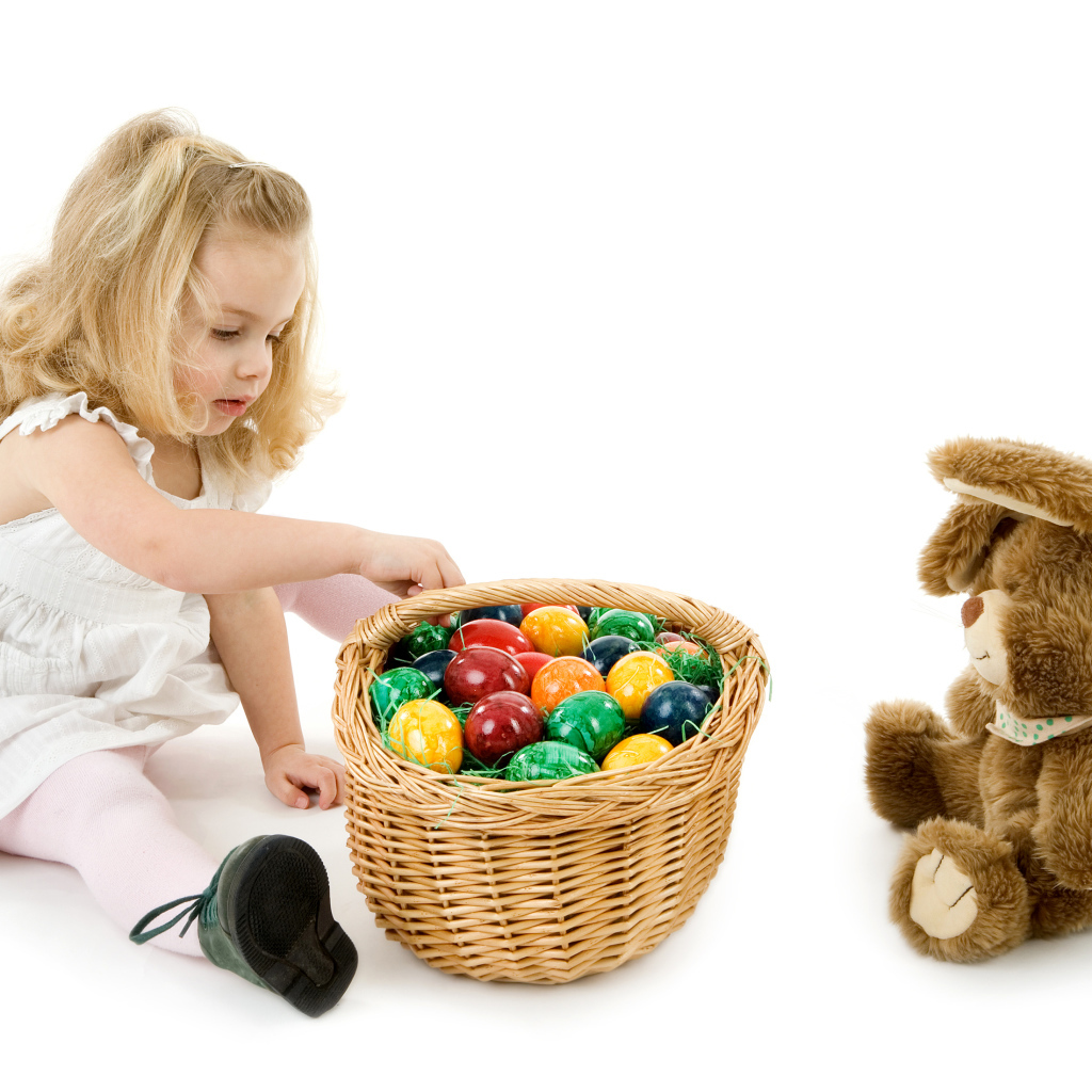 Маленькая девочка с корзиной крашеных яиц и игрушечным кроликом