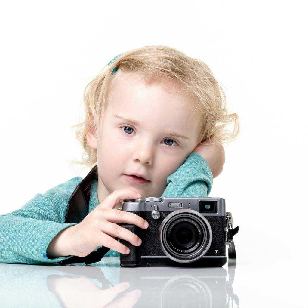 Маленькая девочка с фотоаппаратом на белом фоне