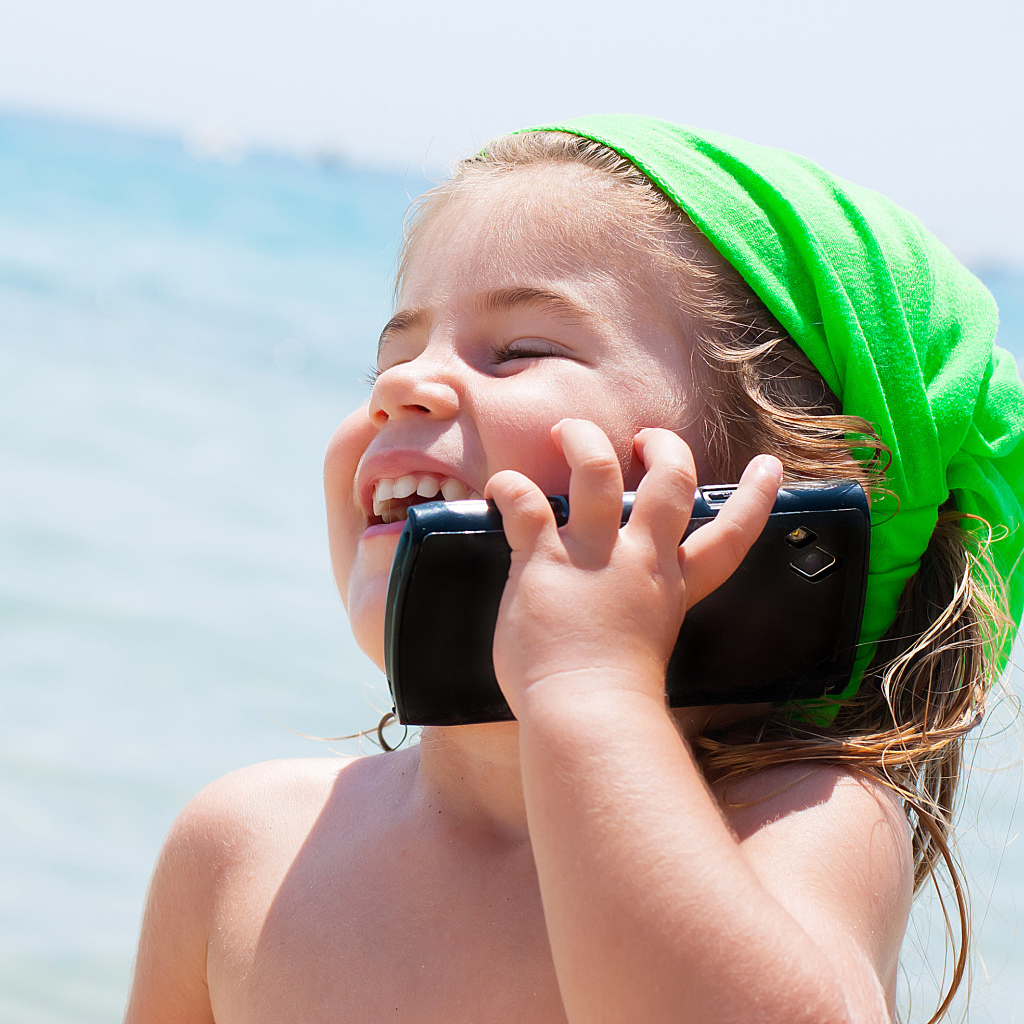 Маленькая девочка с телефоном на пляже