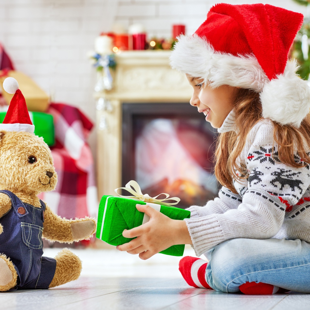 Маленькая девочка с медвежонком Тедди у елки с подарками на Новый год
