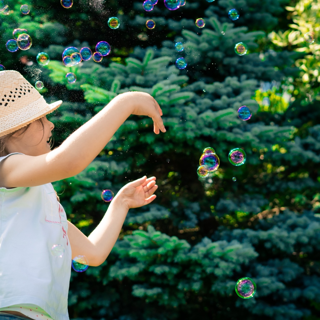 Маленькая девочка с мыльными пузырями у елки