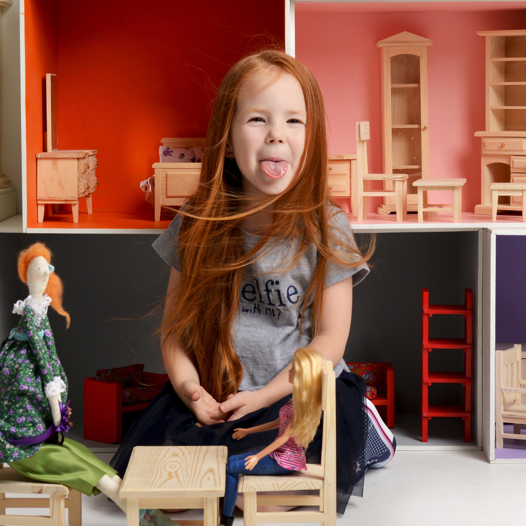 Маленькая длинноволосая девочка показывает язык