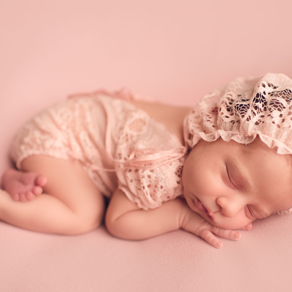 Маленькая новорожденная девочка в розовом костюме 