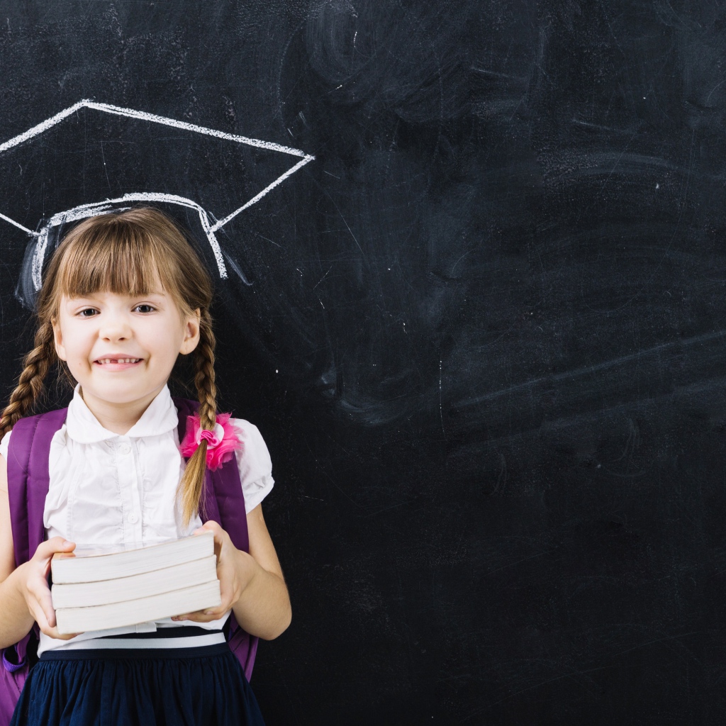 Маленькая школьница с книгами у доски 
