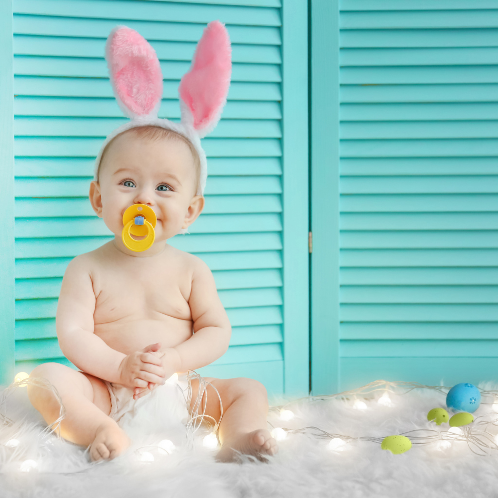 Маленький улыбающийся малыш с ушками зайчика на голове