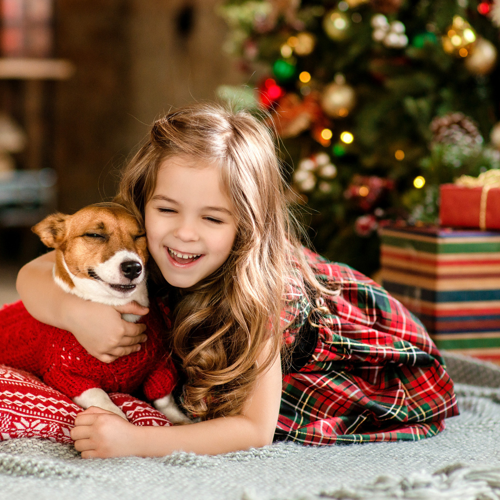 Веселая девочка с собакой у елки 
