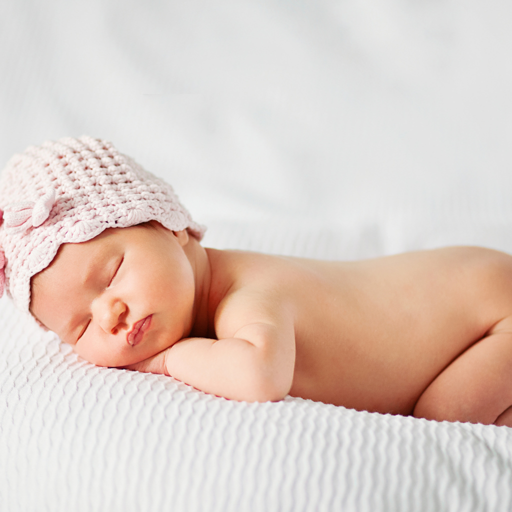 Спящий грудной ребенок девочка на белом покрывале