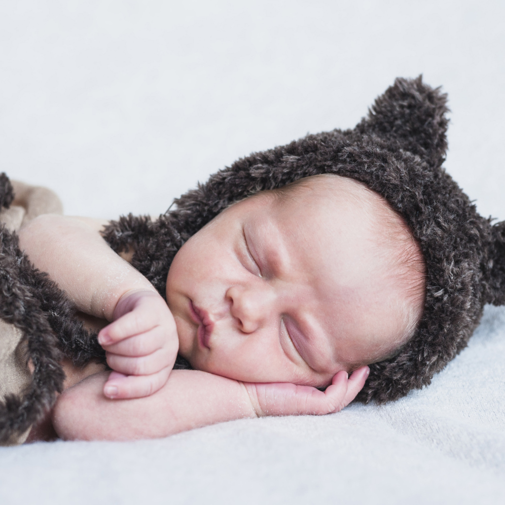 Спящий грудной ребенок в меховой шапке