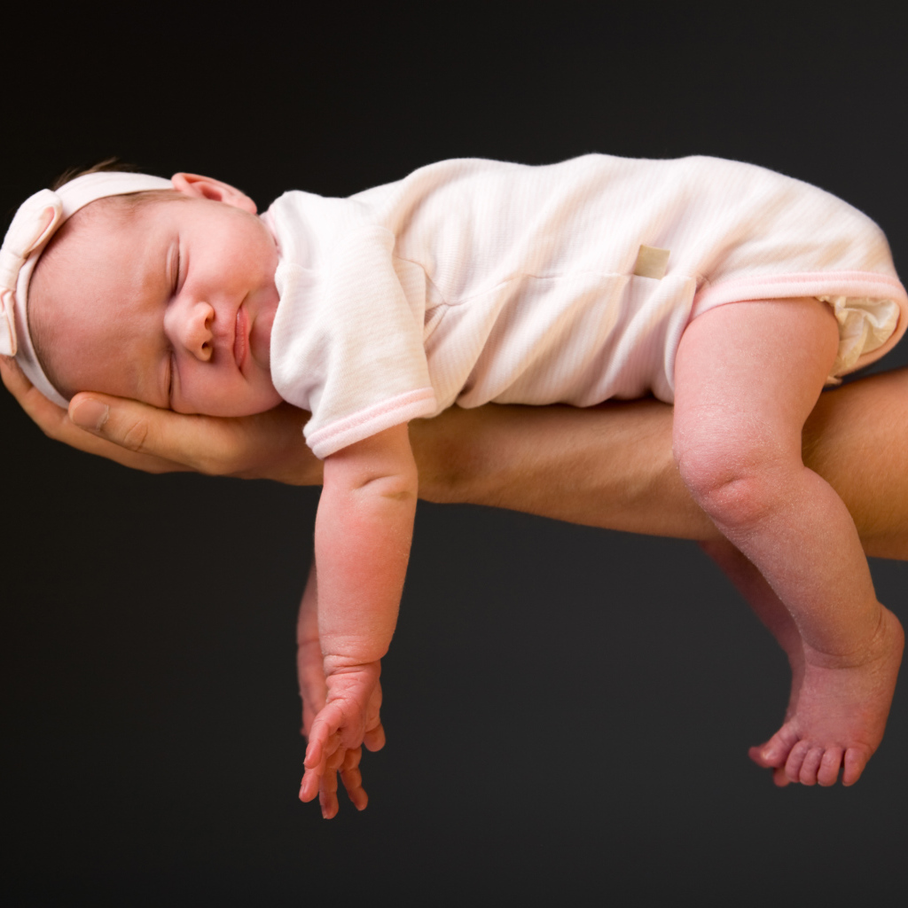 Спящий ребенок на руке у папы на сером фоне