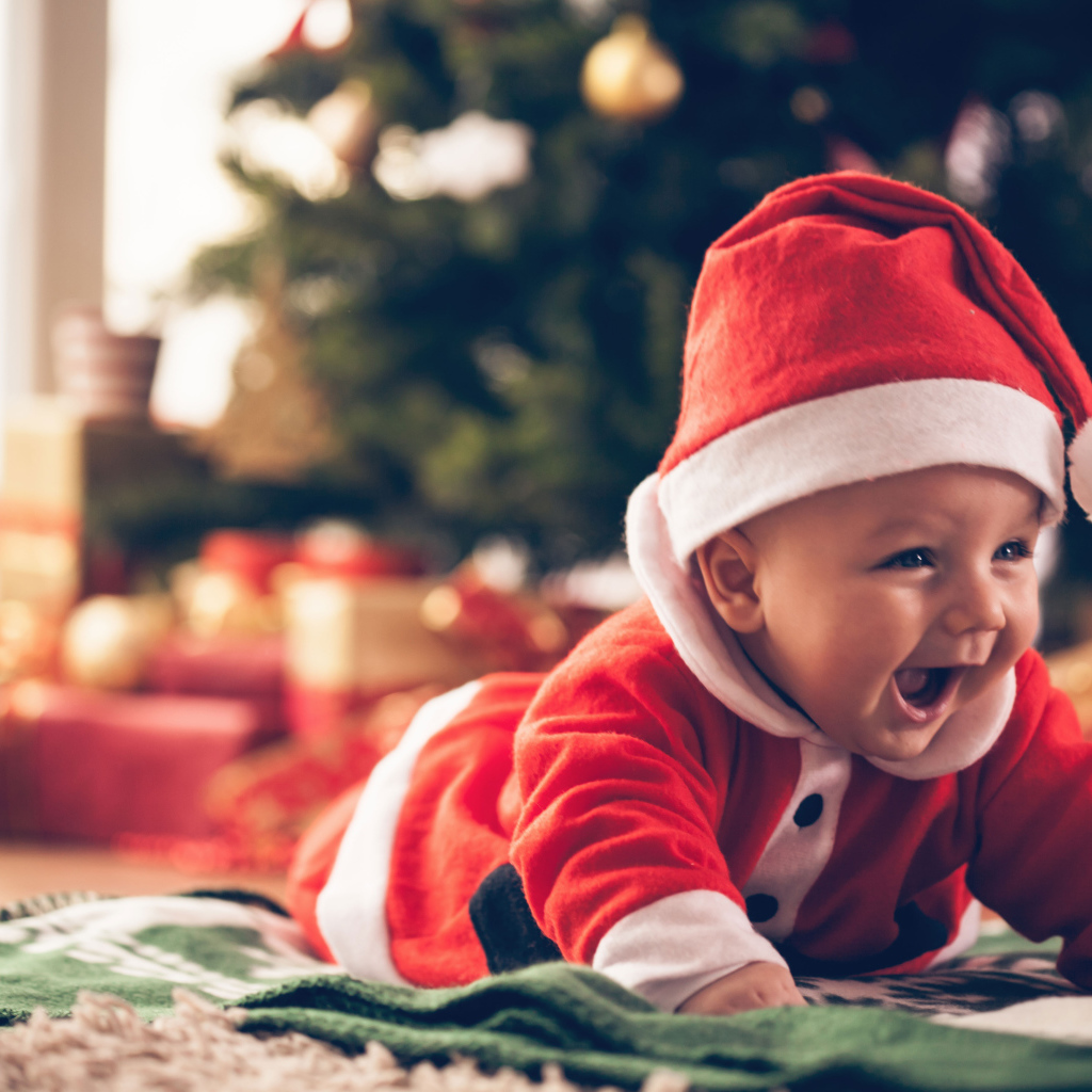 Улыбающийся малыш в новогоднем костюме у елки
