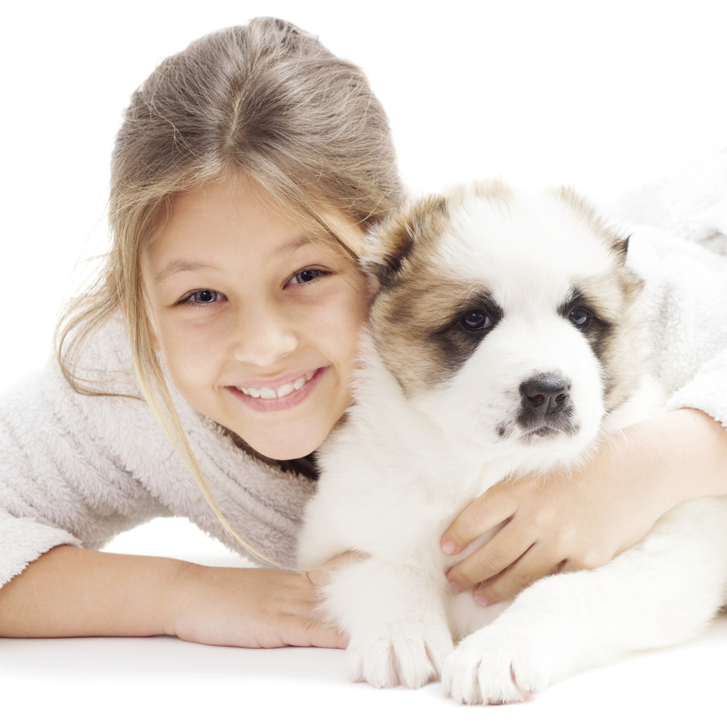 Улыбающаяся девочка лежит с щенком алабая