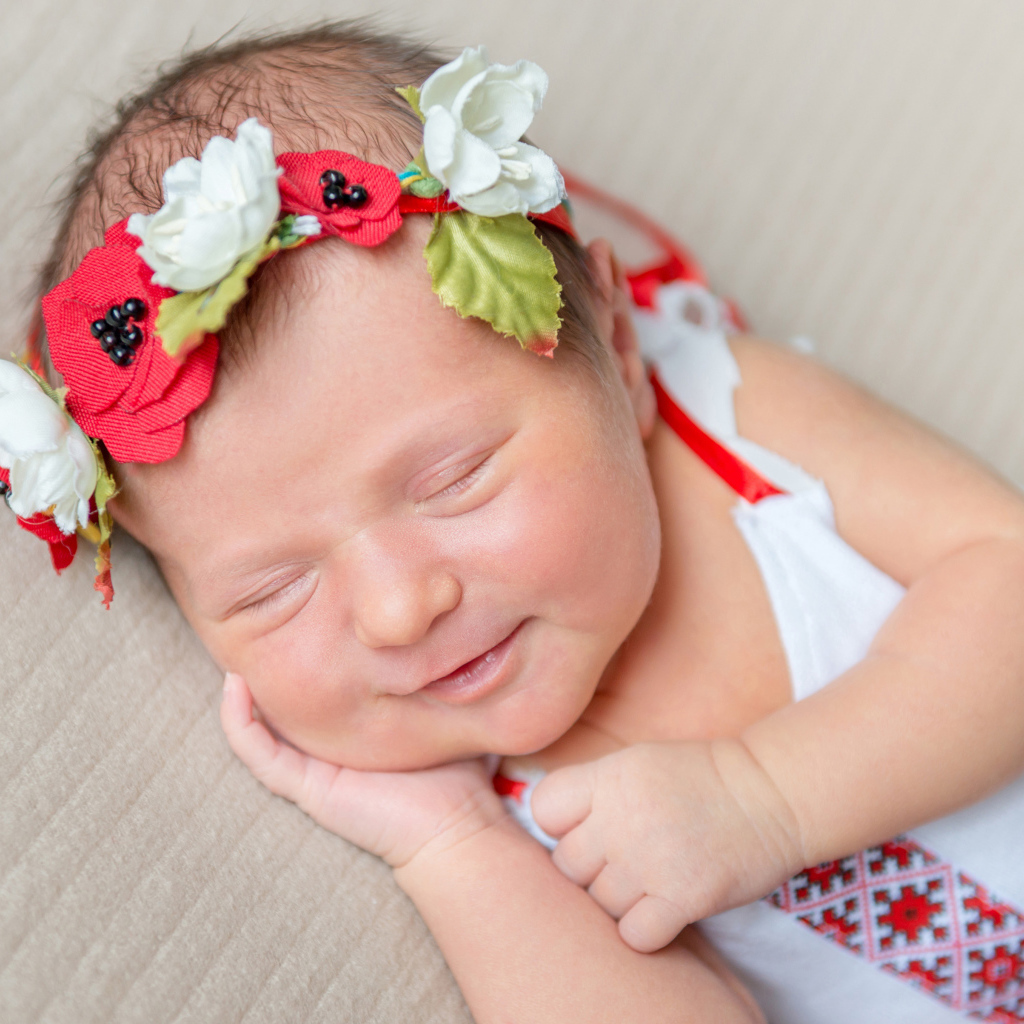Улыбающаяся спящая девочка с венком на голове