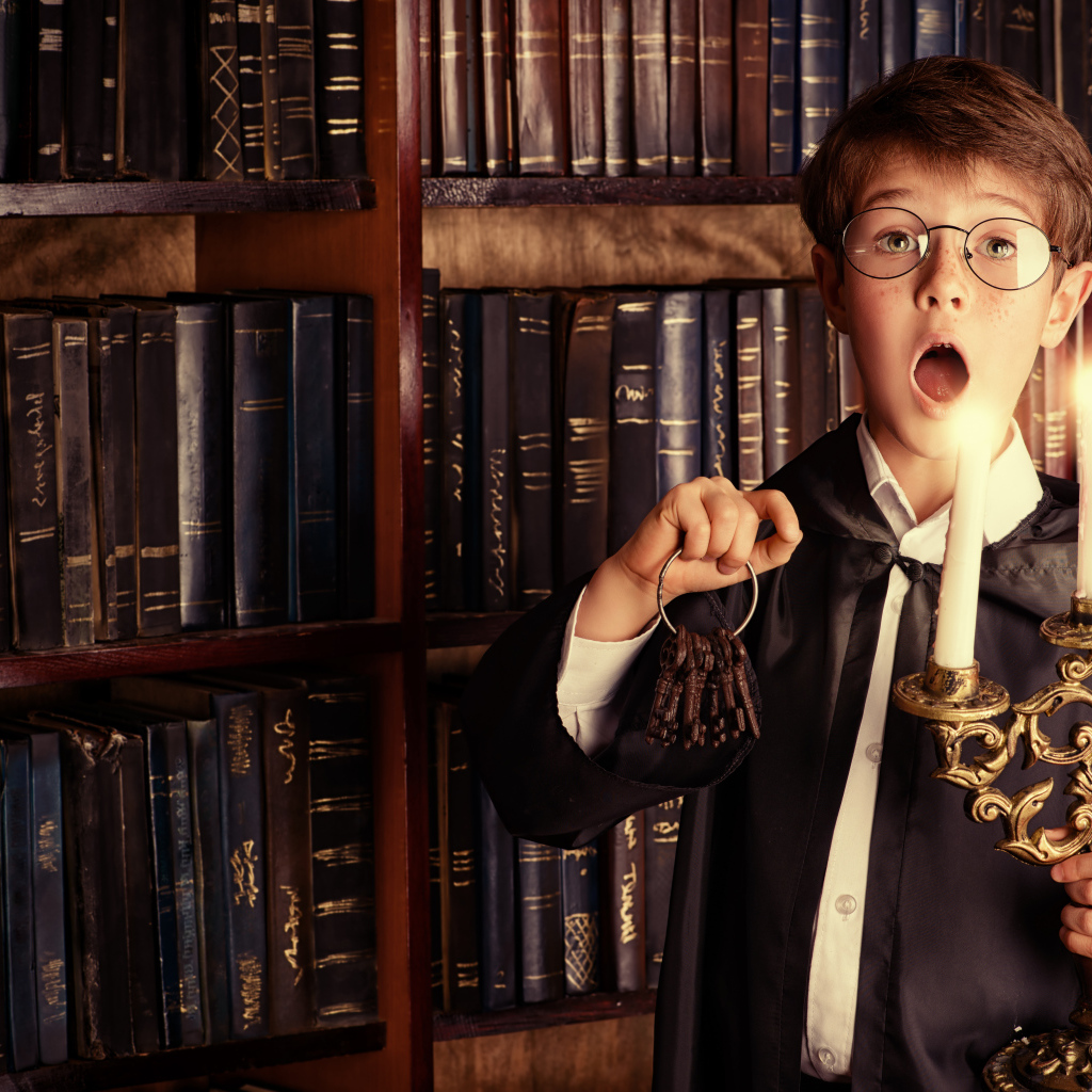 Удивленный мальчик с подсвечником со свечами в библиотеке