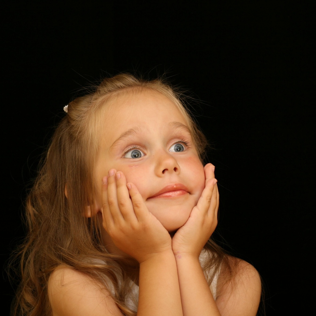 Удивленная маленькая девочка на черном фоне