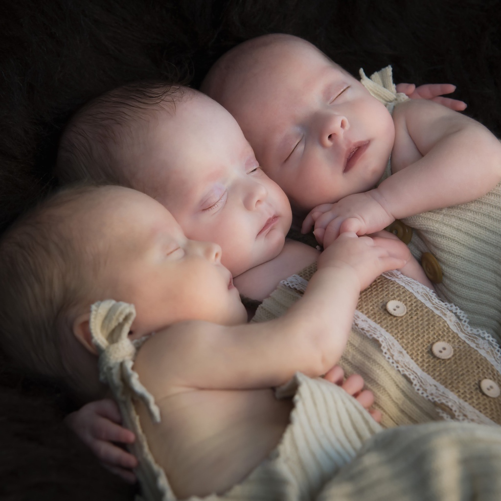 Три маленьких грудных ребенка спят обнявшись 