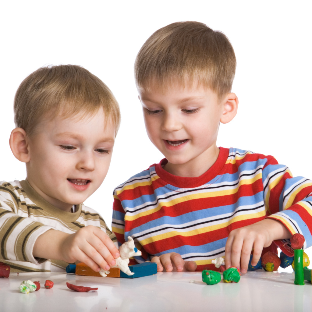 Два мальчика играют в игрушки на белом фоне