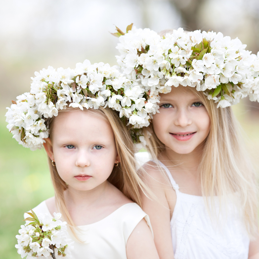 Две милые маленькие девочки с венками из цветов вишни на голове