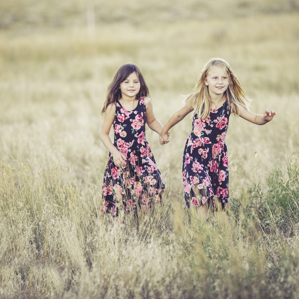 Две маленькие девочки бегут по траве