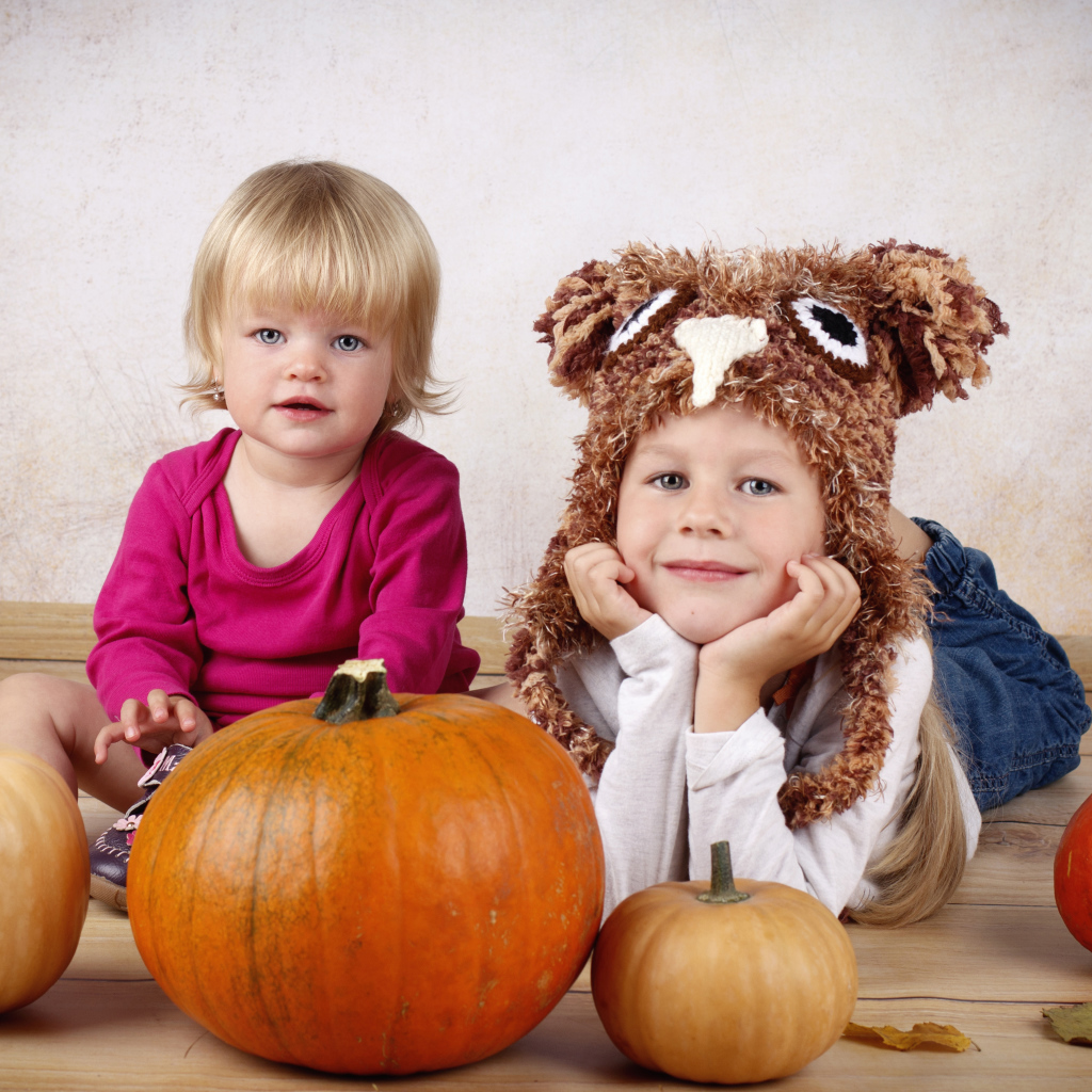 Два маленьких ребенка с тыквами в комнате