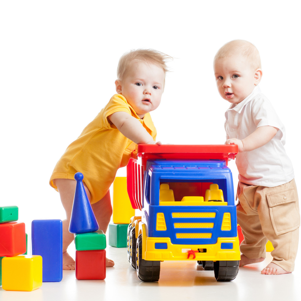 Два маленьких ребенка с игрушками на белом фоне