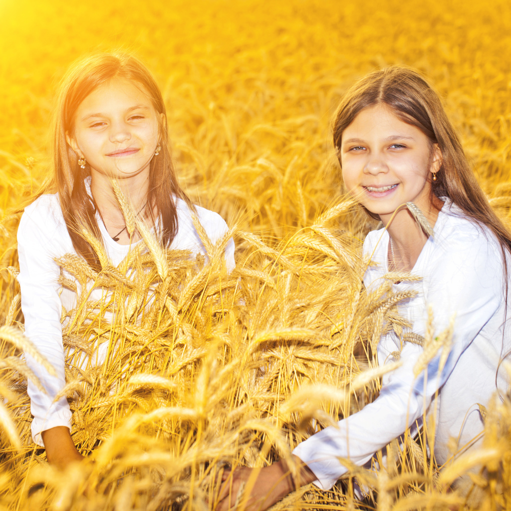 Две улыбающиеся девочки на поле с пшеницей