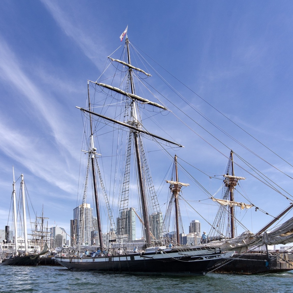 Большая парусная лодка на фоне голубого неба в порту у города