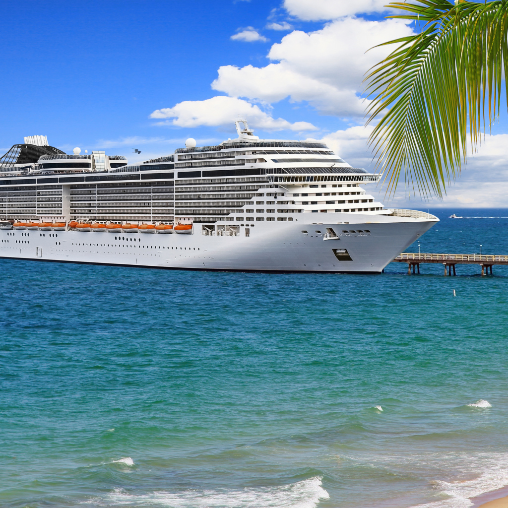 Large white cruise liner at the pier on a tropical beach