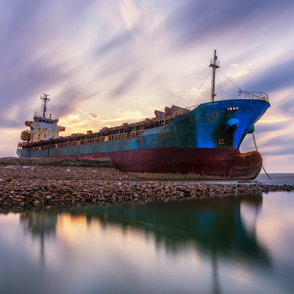 Старый ржавый корабль на берегу под красивым небом