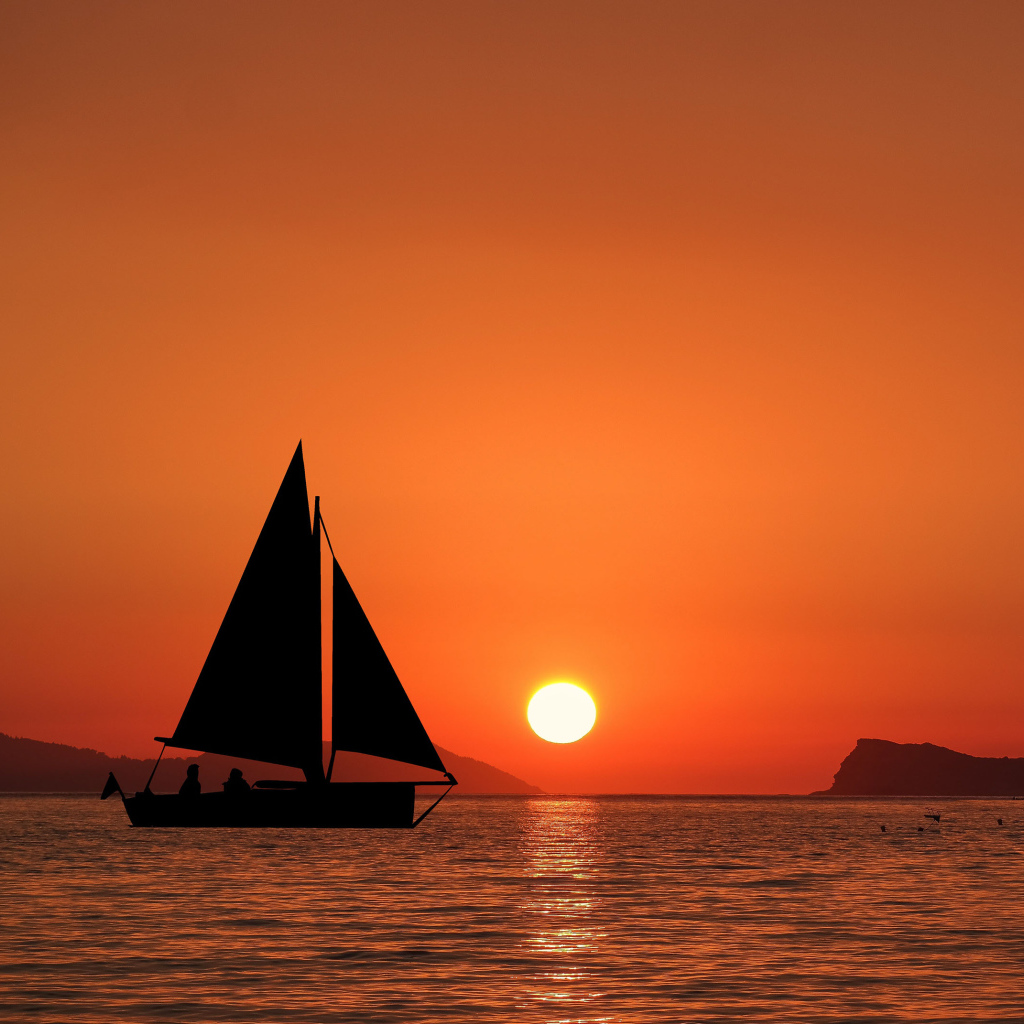 Парусная лодка в море на закате солнца