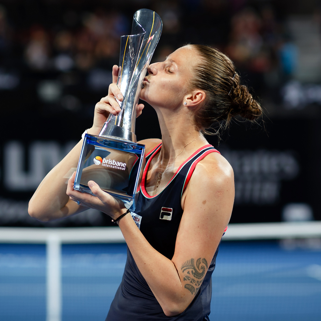 Чешская теннисистка Каролина Плишкова целует кубок на корте