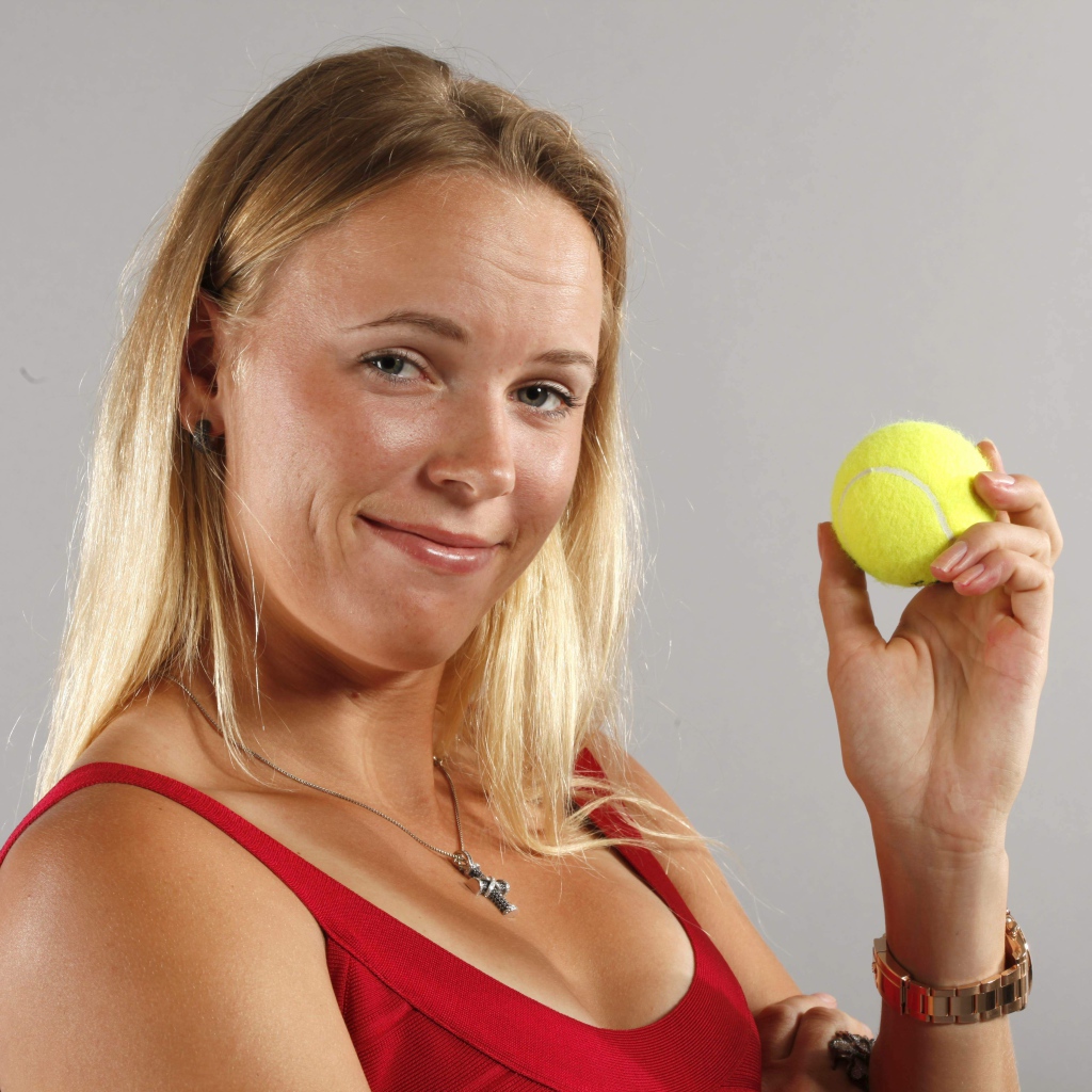 Датская теннисистка Каролина Возняцки с мячиком в руке на сером фоне