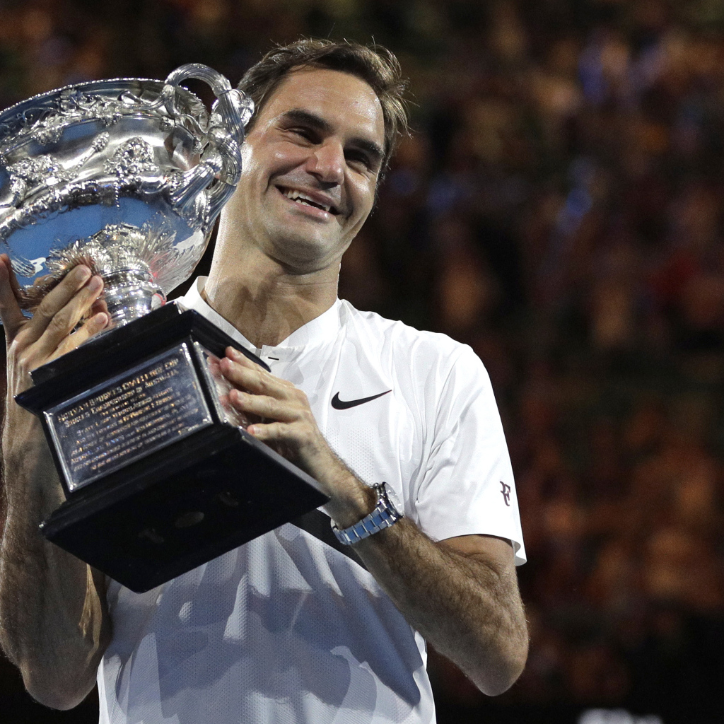 Улыбающийся швейцарский теннисист Роджер Федерер с наградой в руках