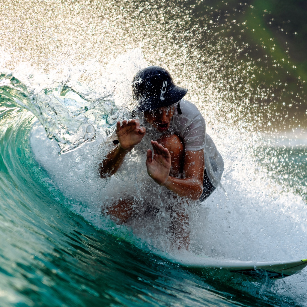 Парень серфингист ловит голубую морскую волну